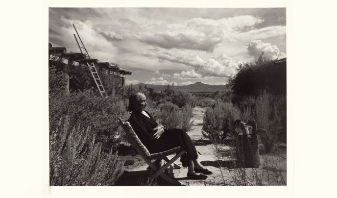 Georgia O’Keeffe sitting in a chair outdoors