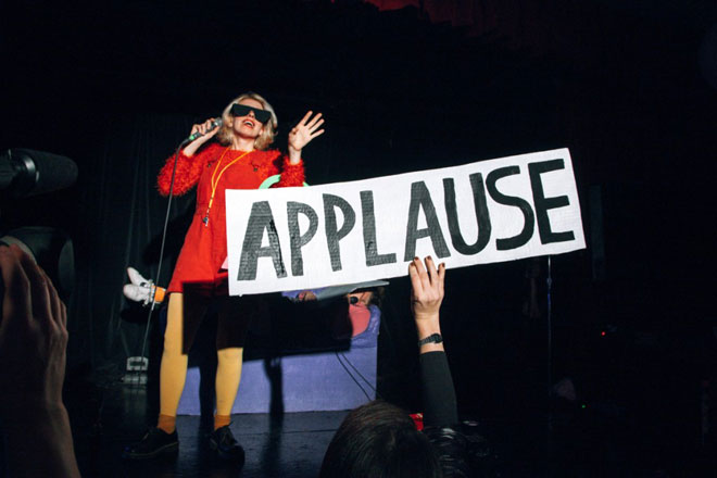 person holding up applause sign at performance